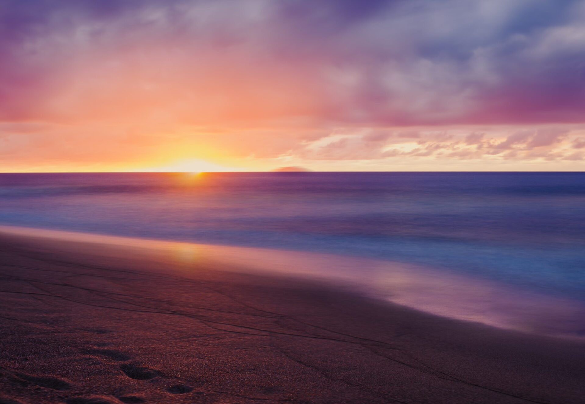 Un couché de soleil sur la mer. Le ciel est dans les ton bleu et rose